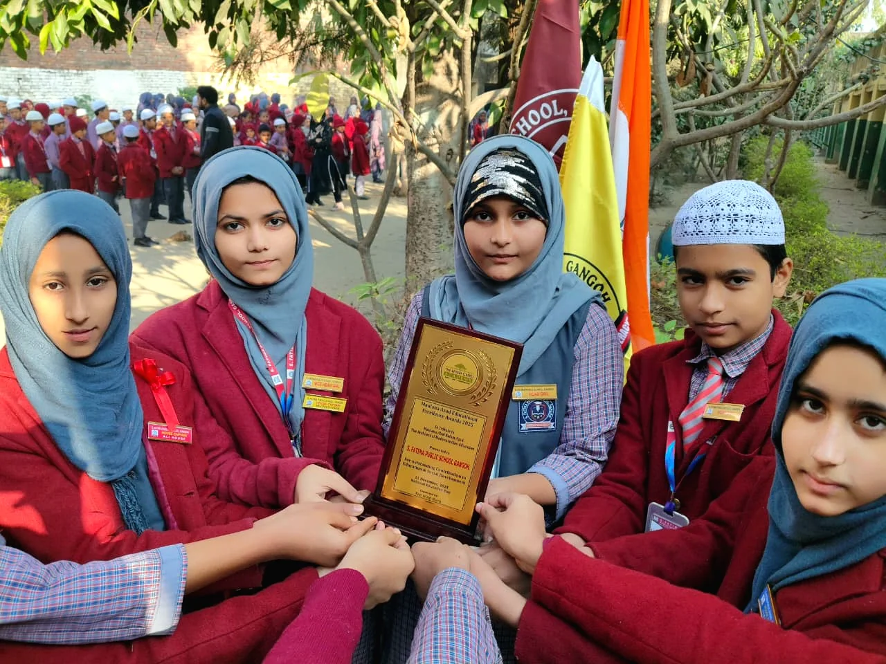 Students pose with a school achievement plaque.